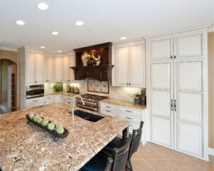 a large kitchen with a center island and marble counter tops.