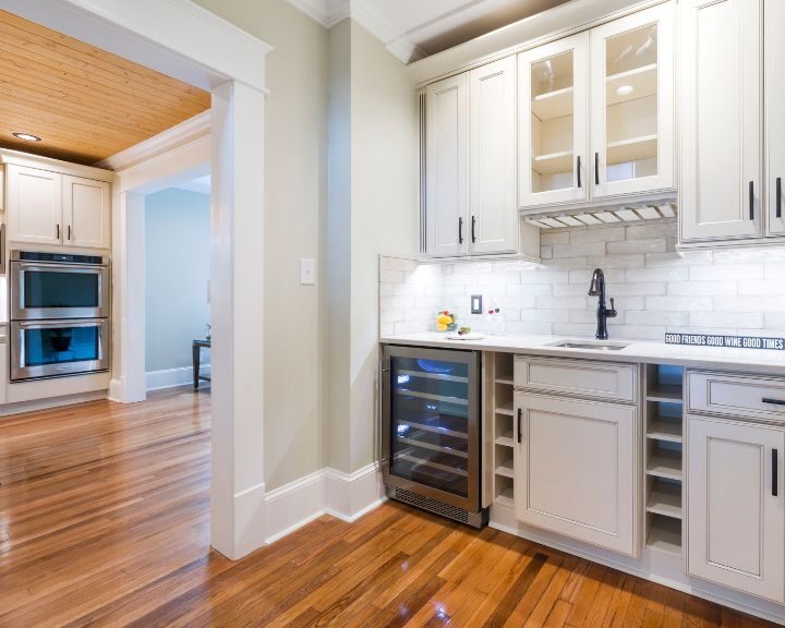 a kitchen with white cabinets and wood floors.