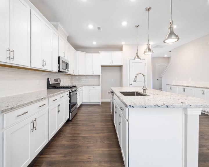 a kitchen with white cabinets and marble counter tops.