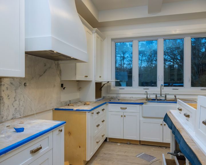 a kitchen with white cabinets and marble counter tops.