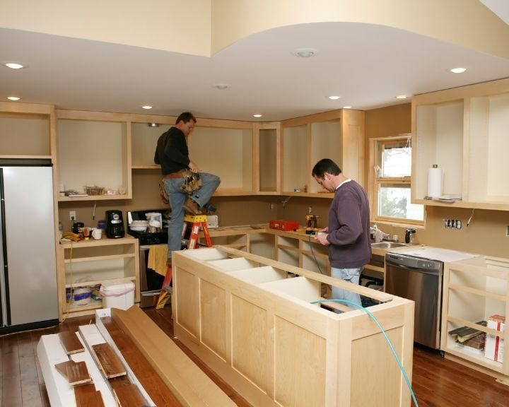 two men working in a kitchen under construction.