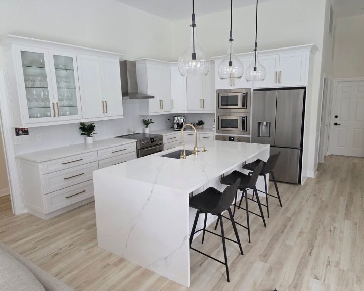 luxury-kitchen-refurbishment-sarasota-fl-720x576px Modern white kitchen with marble island and stools.