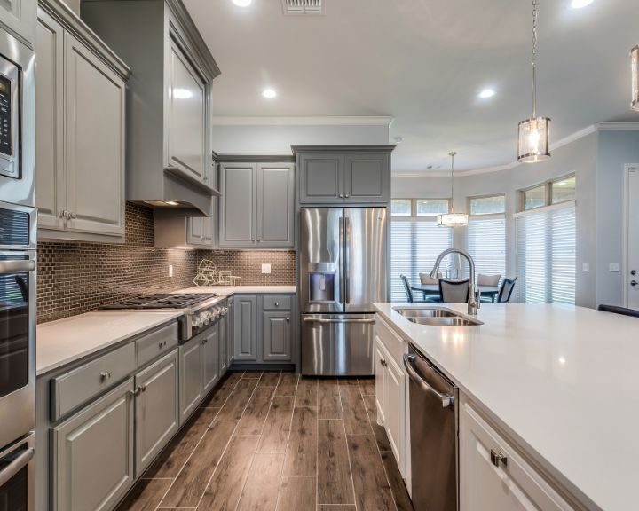 a large kitchen with stainless steel appliances and white counter tops.